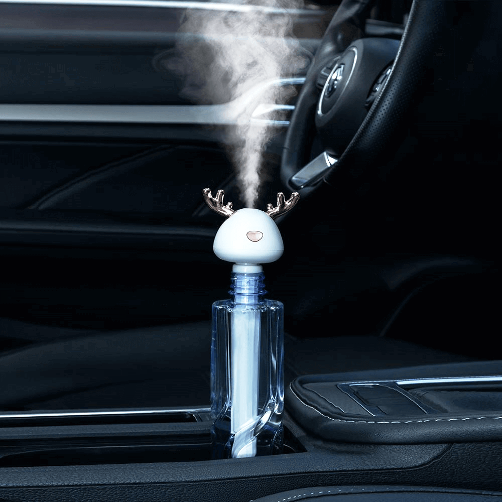White Ava portable humidifier in glass bottle - sitting in black leather center console of car