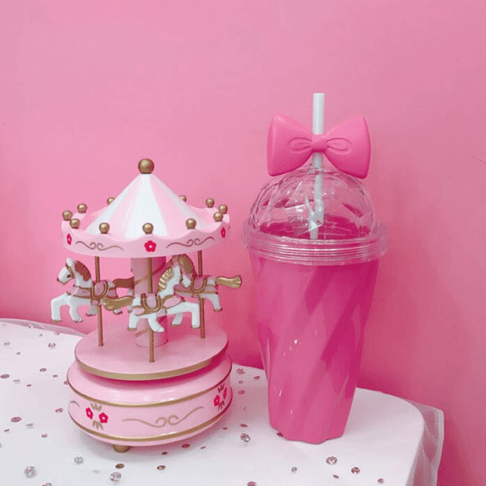 Hot pink Belle bow cup next to pink toy carousel - hot pink background - home & office