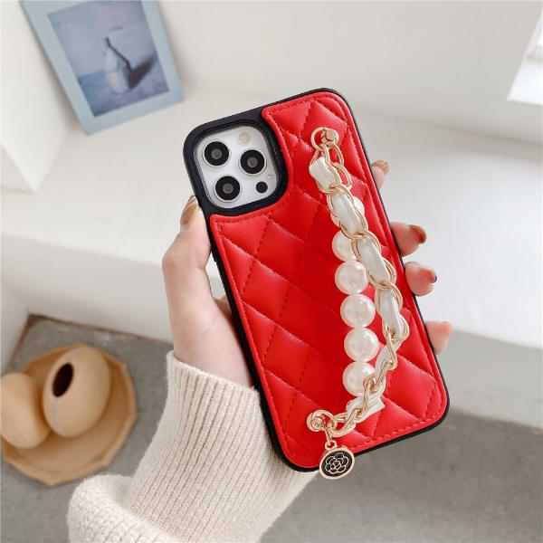 Hand holding red Claire Camelia Quilted Phone Case with pearls and fabric laced chain and camelia emblem
