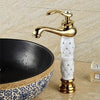 Coco glam faucet - home & office. Tall tap over elaborate ornamental bowl sink. White core and gold fixture matches the white and gold of the decorated elevated sink against the tiled counter and wall