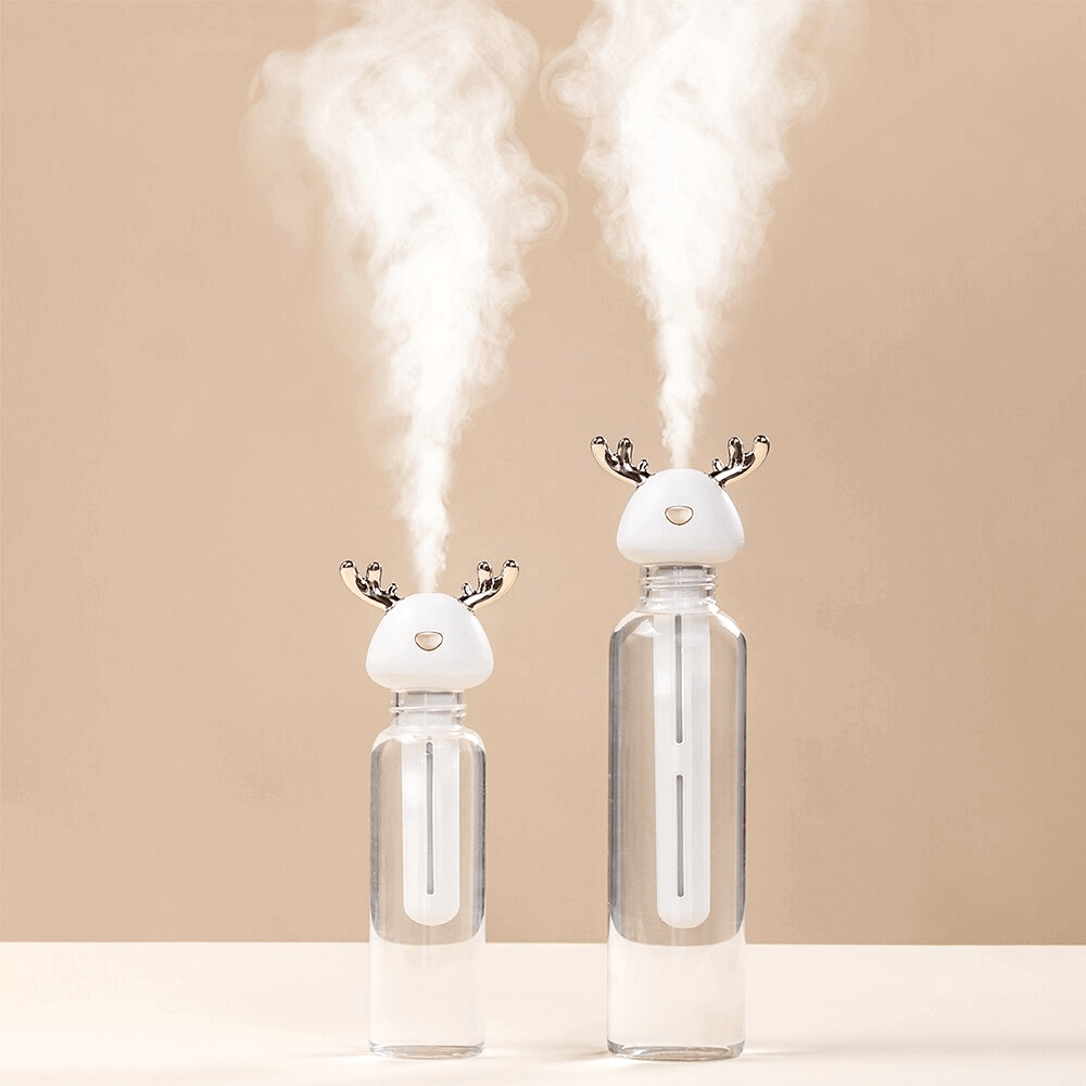 Short & tall Ava portable humidifiers in glass bottles on white table - mauve background - mist in air
