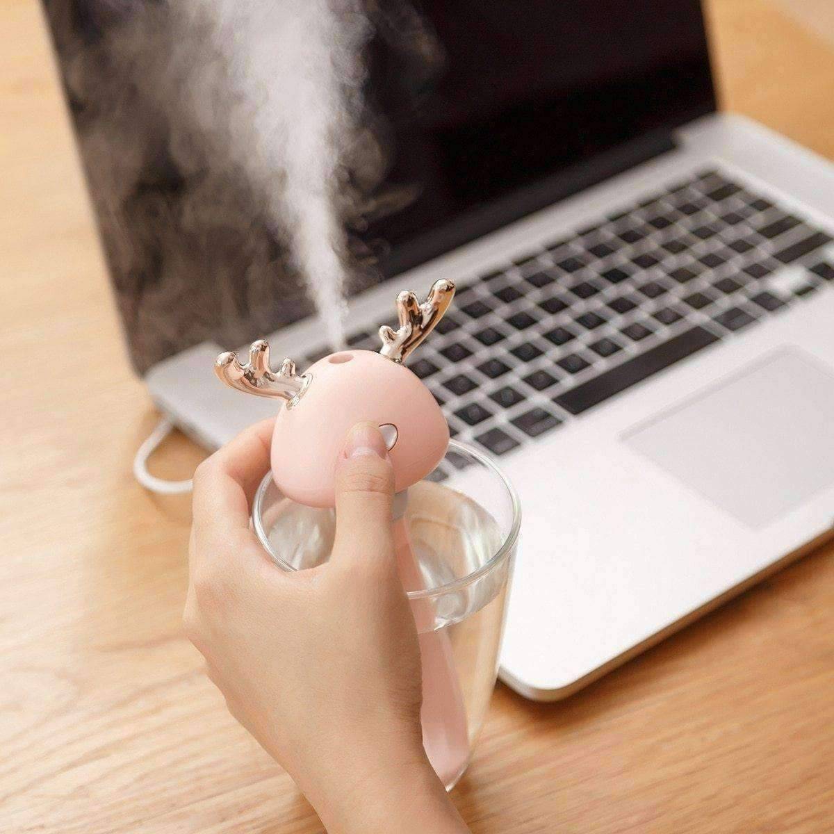 Pink Ava portable humidifier - beauty & wellness - Girl Pressing button on humidifier in front of laptop on wooden desk 