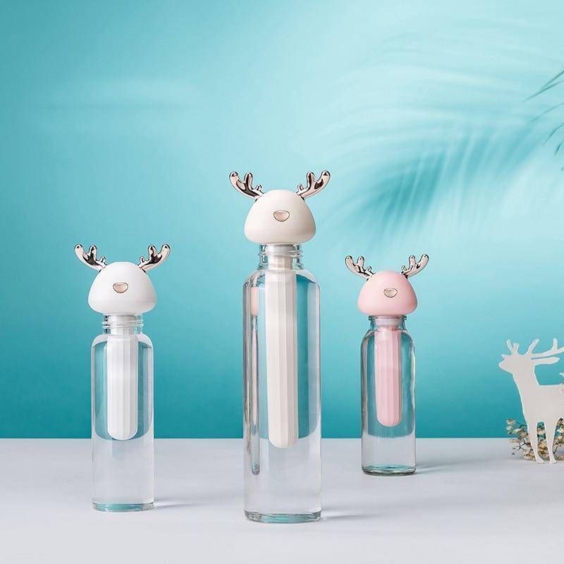 White Cream & Pink Ava portable humidifiers in glass bottles on white table - Cyan background with palm leaf shadow