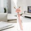 Pink Ava portable humidifier creating mist in glass filled with water - on white table in white living room