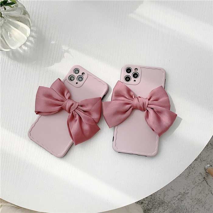 Pair of Matte Minimalist Paris Pink Belle Bow Case showing back of phone and linen bows on white table
