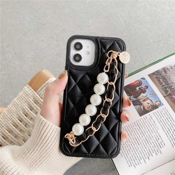 Hand holding black Claire Camelia Quilted Phone Case with pearls and fabric laced chain and camelia emblem