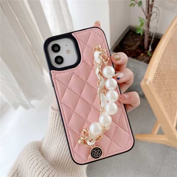 Hand holding pink Claire Camelia Quilted Phone Case with pearls and fabric laced chain and camelia emblem