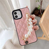 Load image into Gallery viewer, Hand holding pink Claire Camelia Quilted Phone Case with pearls and fabric laced chain and camelia emblem
