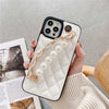 Hand holding white Claire Camelia Quilted Phone Case with pearls and fabric laced chain and camelia emblem
