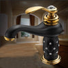 Coco glam faucet - 5 / short - home & office. Gold faucet and trim on black spout and stem give a dark rich background for the glitter aesthetic of the embedded crystals. Background shows deep browns and beige ceramic and marbles
