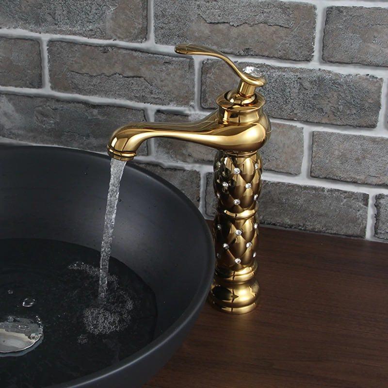 Coco glam faucet - 6 / tall - home & office. Exotic look of the gold on gold tall faucet open over a black elevated sink on dark polished wood surface. Water bubbles and in sink as aerator reduces splash and controls flow.