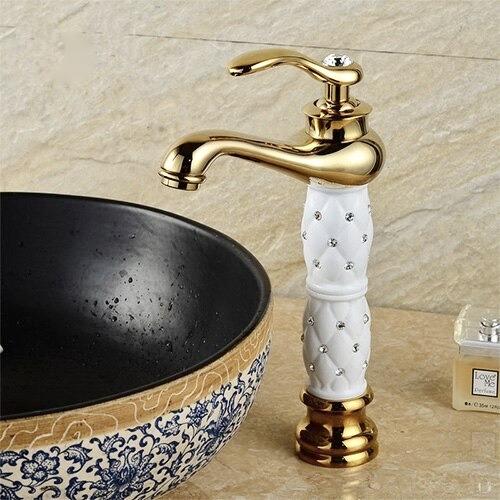 Coco glam faucet - home & office. Tall tap over elaborate ornamental bowl sink. White core and gold fixture matches the white and gold of the decorated elevated sink against the tiled counter and wall