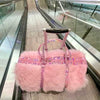 Load image into Gallery viewer, Weekender bag made of pink faux fur and iridescent pink faux leather handles and shoulder strap used as a carry-on bag sitting on a suitcase traveling down an escalator at the airport.